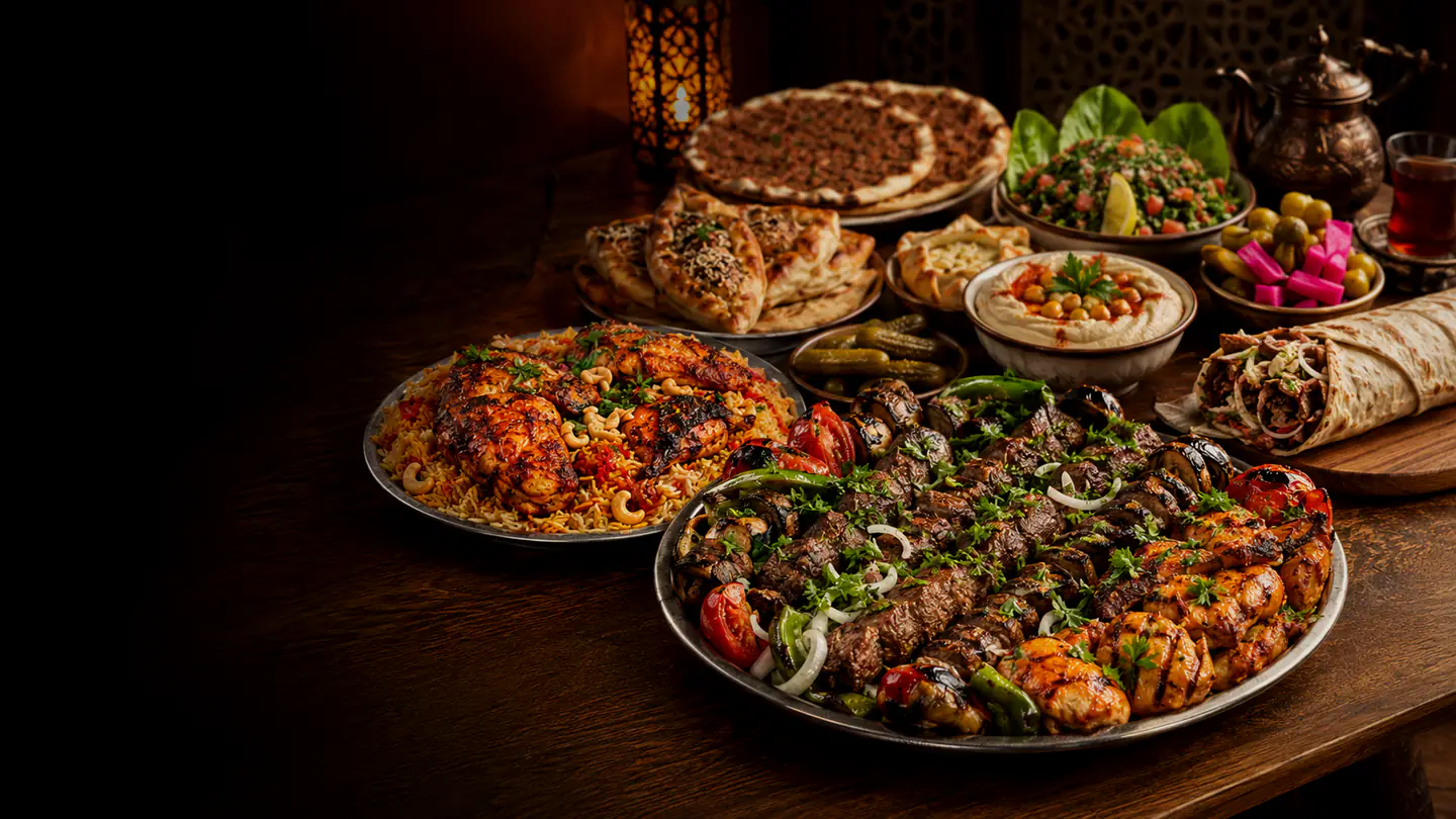 مائدة شامية تضم صحن المشاوي المشكّلة ودجاجاً مشوياً مع الأرز الملوّن والشاورما واللحم بعجين والمعجنات الصغيرة والحمص والتبولة والمخللات والشاي.