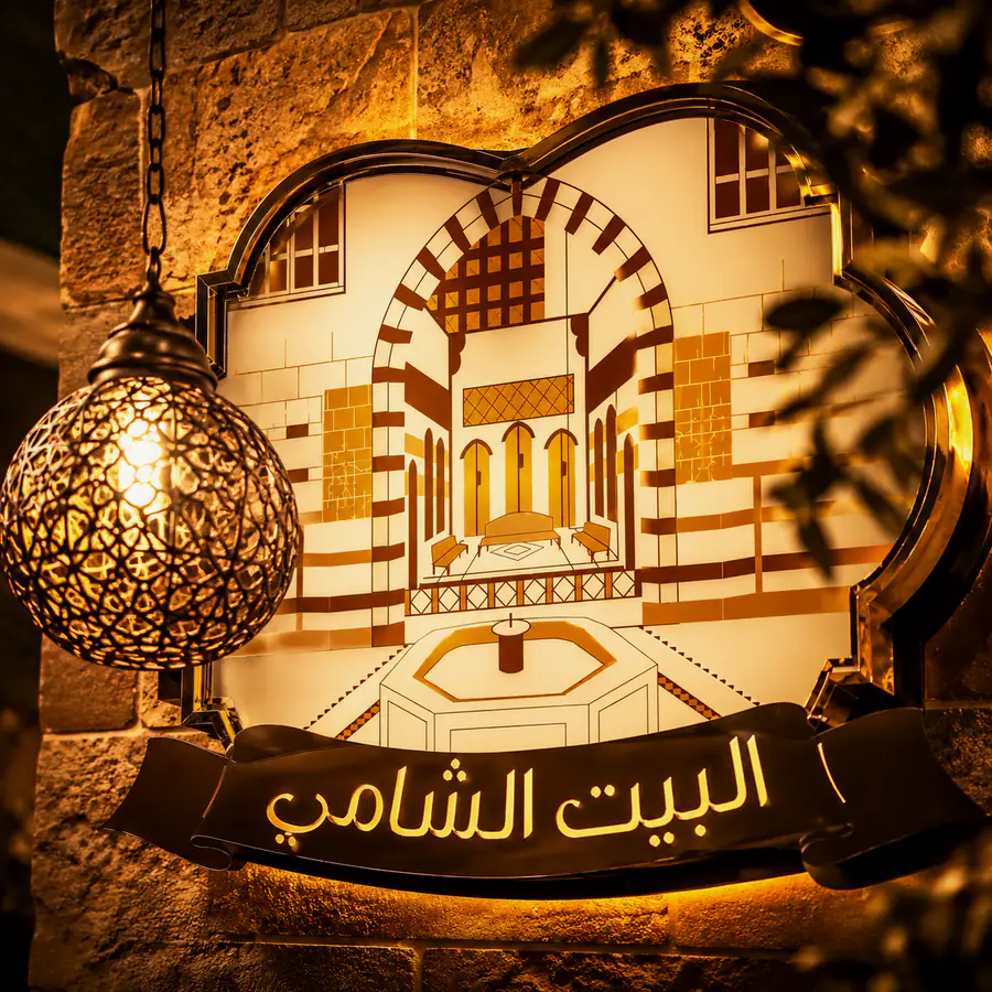 لوحة البيت الشامي المضاءة داخل المطعم.
